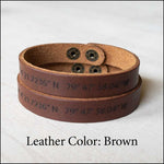 a set of two matching couples bracelets engraved with custom navigation coordinates. The bracelets are made with brown leather and brass snaps. 