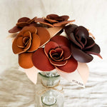 A bouquet of leather roses in different colors with metal stems in a vase. Engraved with names as a 3rd anniversary gift.